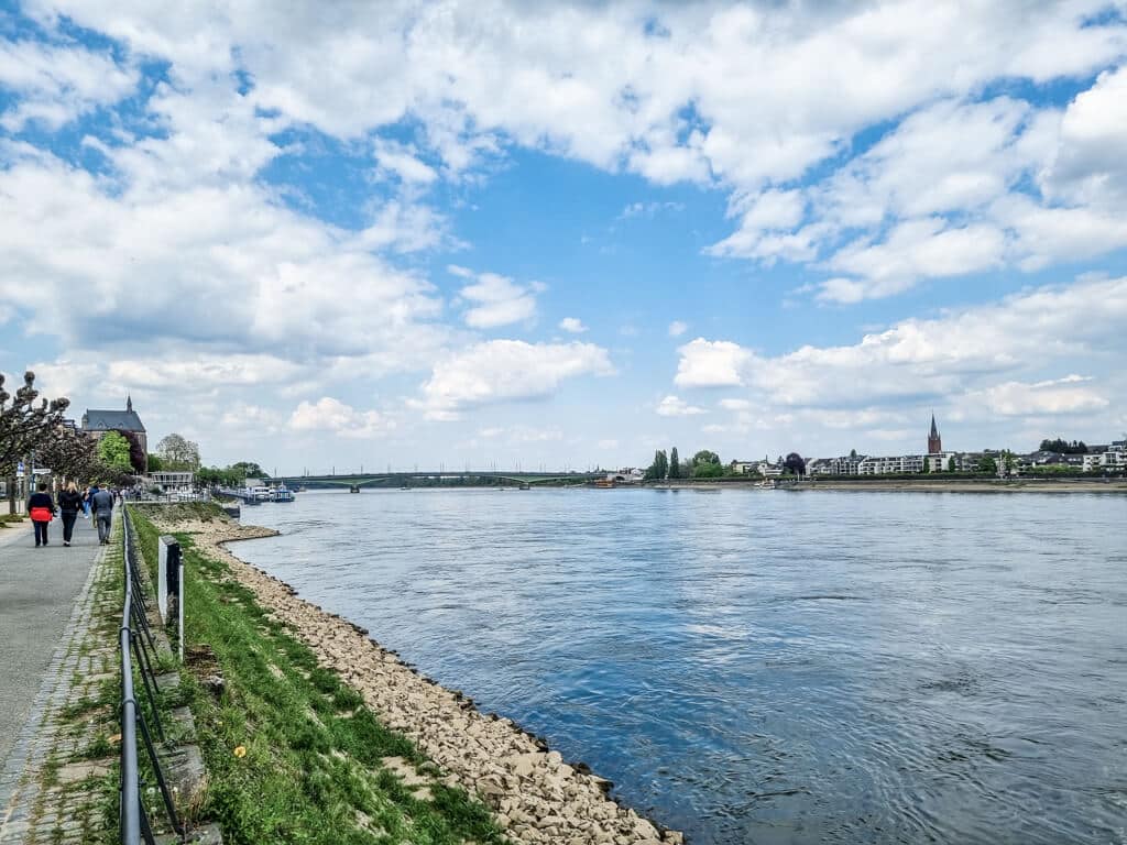 Weg entlang des Rheinufers, rechts davon der Rhein und der Stadtteil Bonn-Beuel
