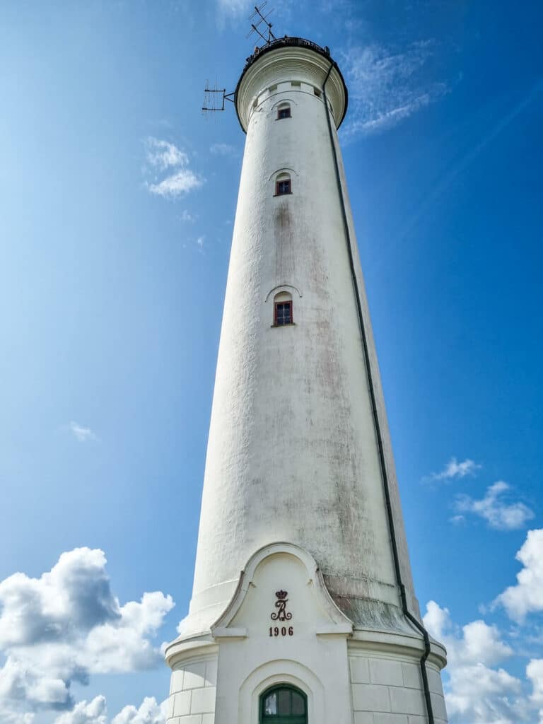 runder, weißer Leuchtturm von unten fotografiert vor blauem Himmel