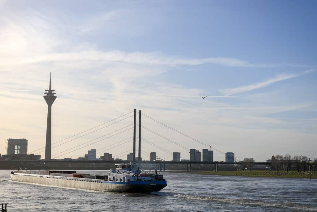 Boot fährt auf dem Rhein - dahinter eine Brücke und der Fernsehturm