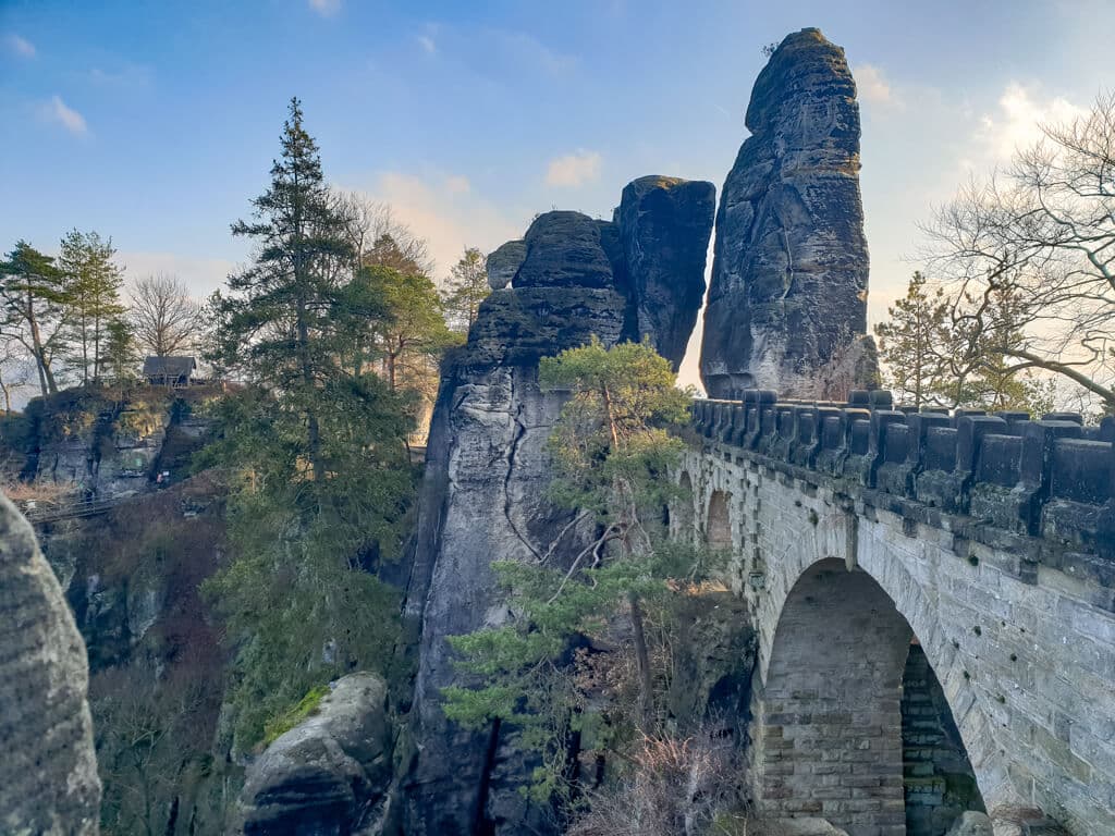 Steinbrücke mit Rundbögen inmitten von Felsen und Bäumen