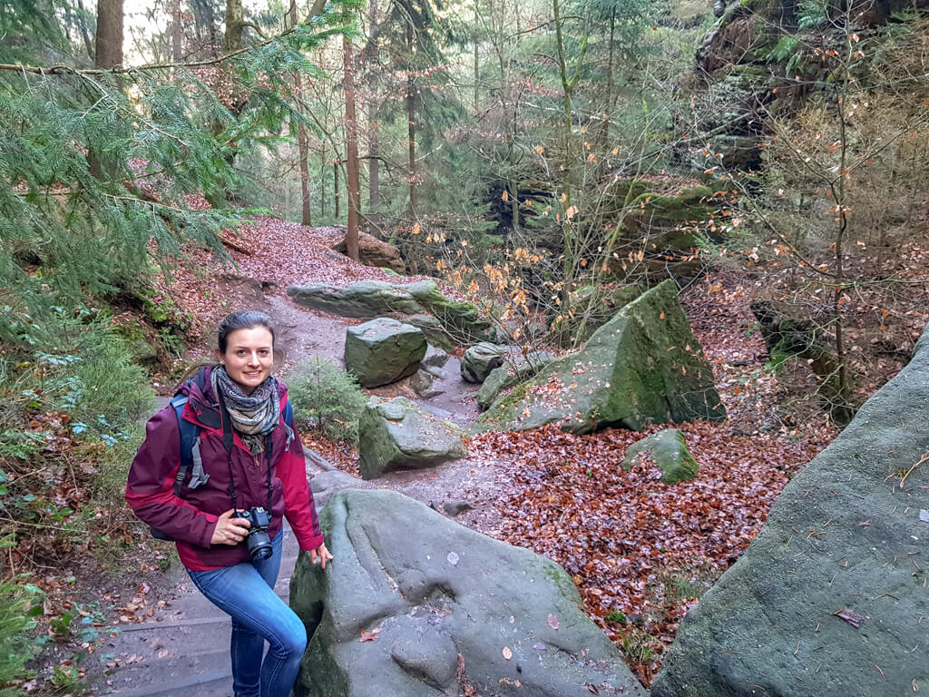 Frau steht auf steinigem Wanderweg im Wald