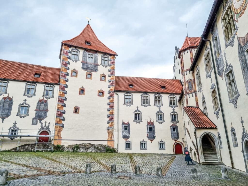 Innenhof des Hohen Schloss in Füssen. Platz aus Kopfsteinpflaster umgeben von Gebäuden mit kunstvoll 3-Dimensional bemalten Fenstern