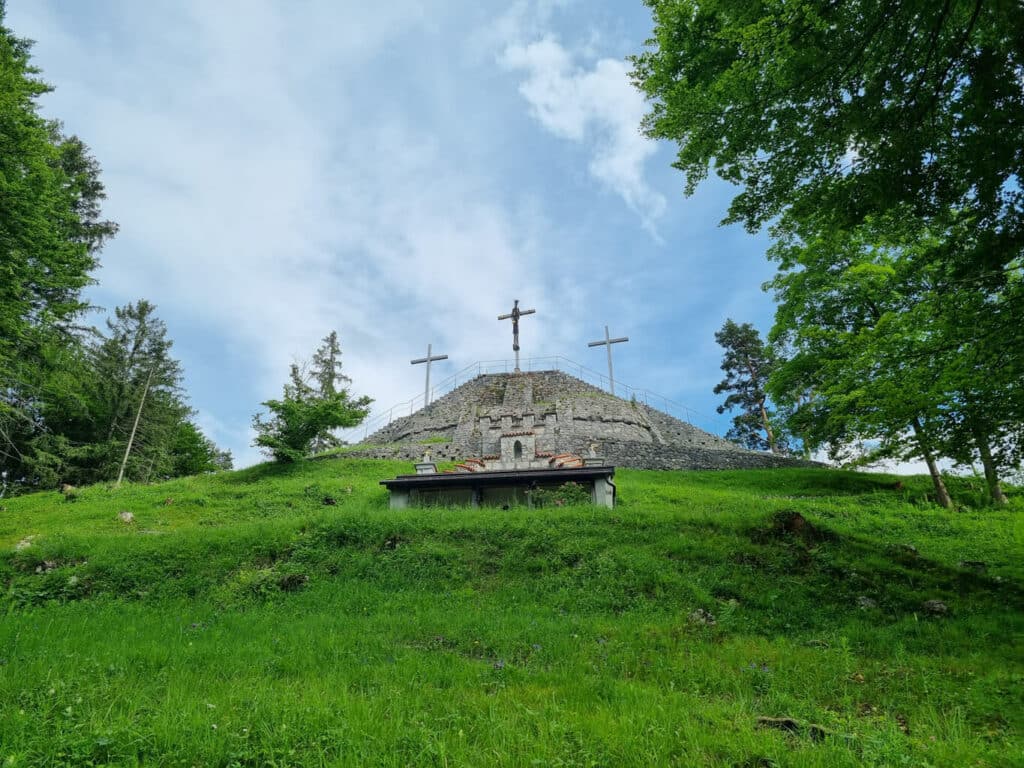 Drei Kreuze stehen auf dem Kalvarienberg in Füssen auf einem grünen Hügel