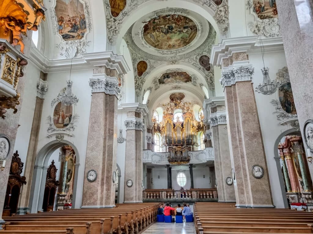 Blick in die kunstvoll verzierte Pfarrkirche St. Mang in Füssen mit hohen Säulengängen und Malereien an der Decke