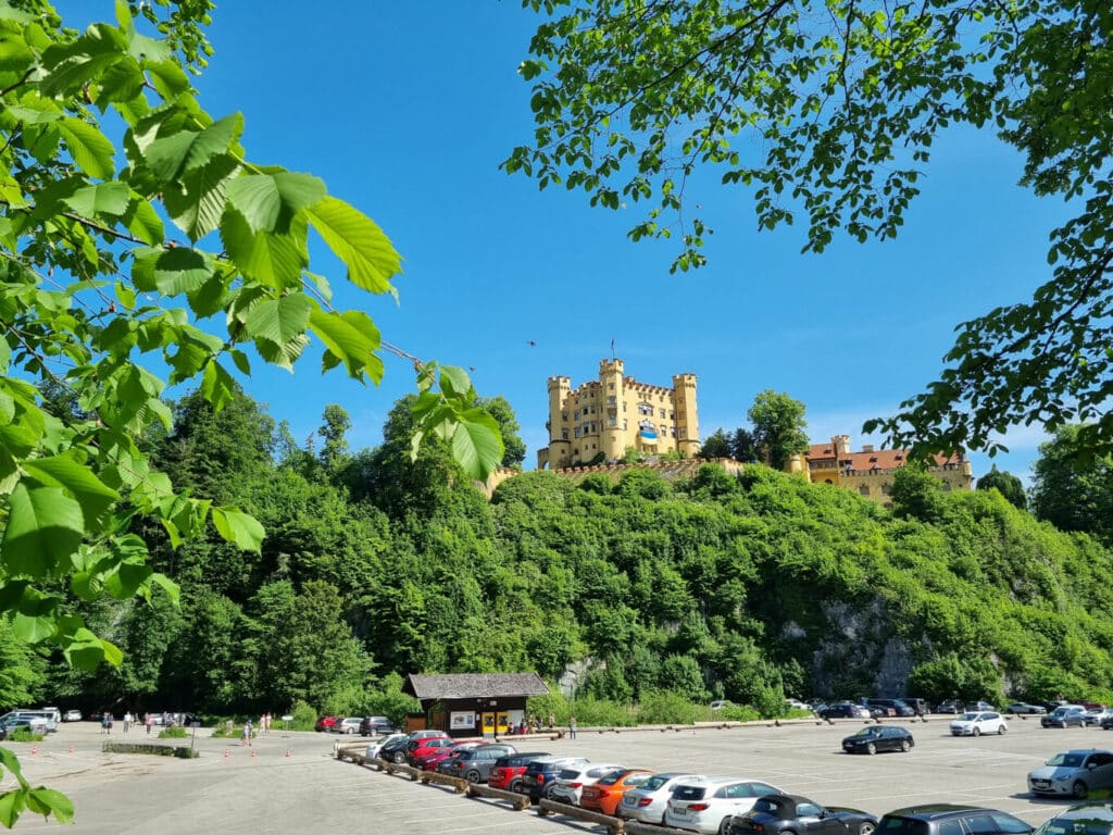 Blick über einen Parkplatz zum höher gelegenen Schloss Hohenschwangau