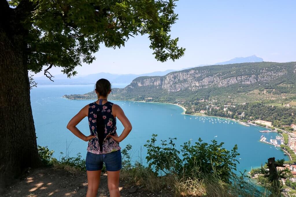 Frau steht auf einem Hügel mit Blick auf den Gardasee und die Küstenlinie