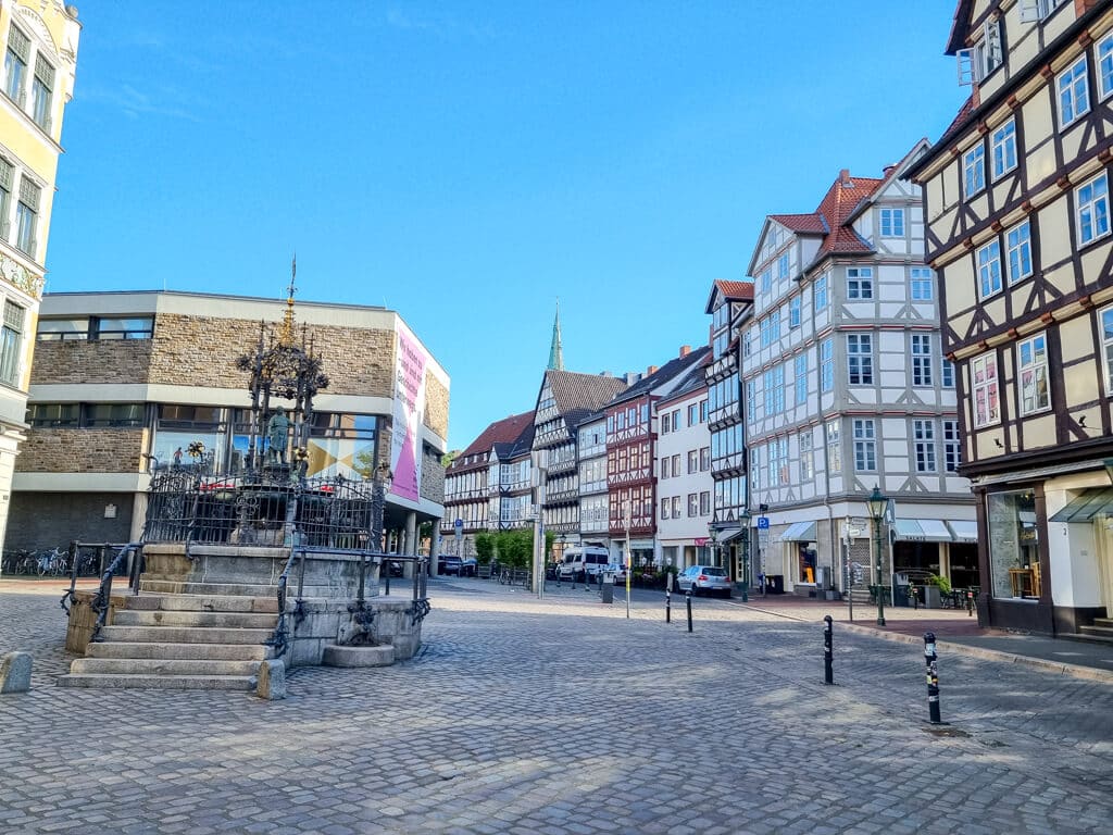 Innenstadt mit Kopfsteinpflaster - linksseitig ein verzierter Brunnen, rechtsseitig einige Fachwerkhäuser