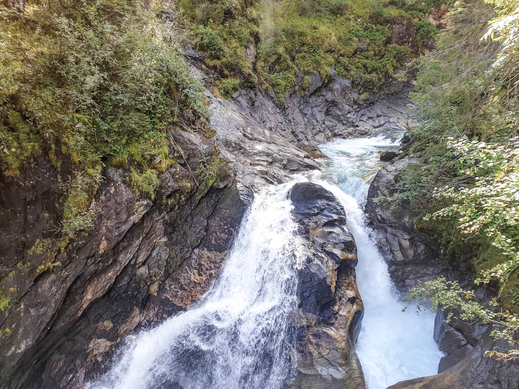 Wasserfall teilt sich an einem Stein und fließt durch den Berg