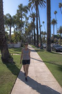 Beverly Hills - Frau läuft über Gehweg mit Palmen