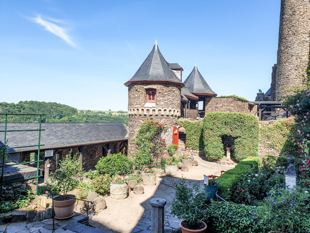 Innenhof der Burg Thurant mit Ecktürmen und Pflanzen an einem Weg