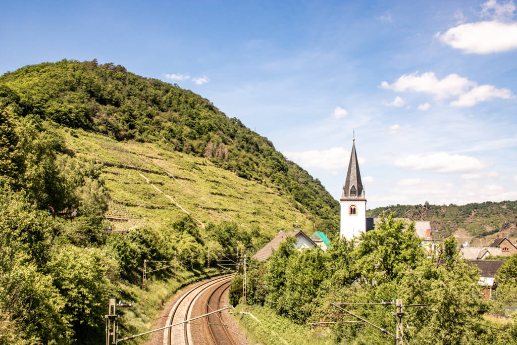 kleiner Kirchturm inmitten von grünen Hügeln