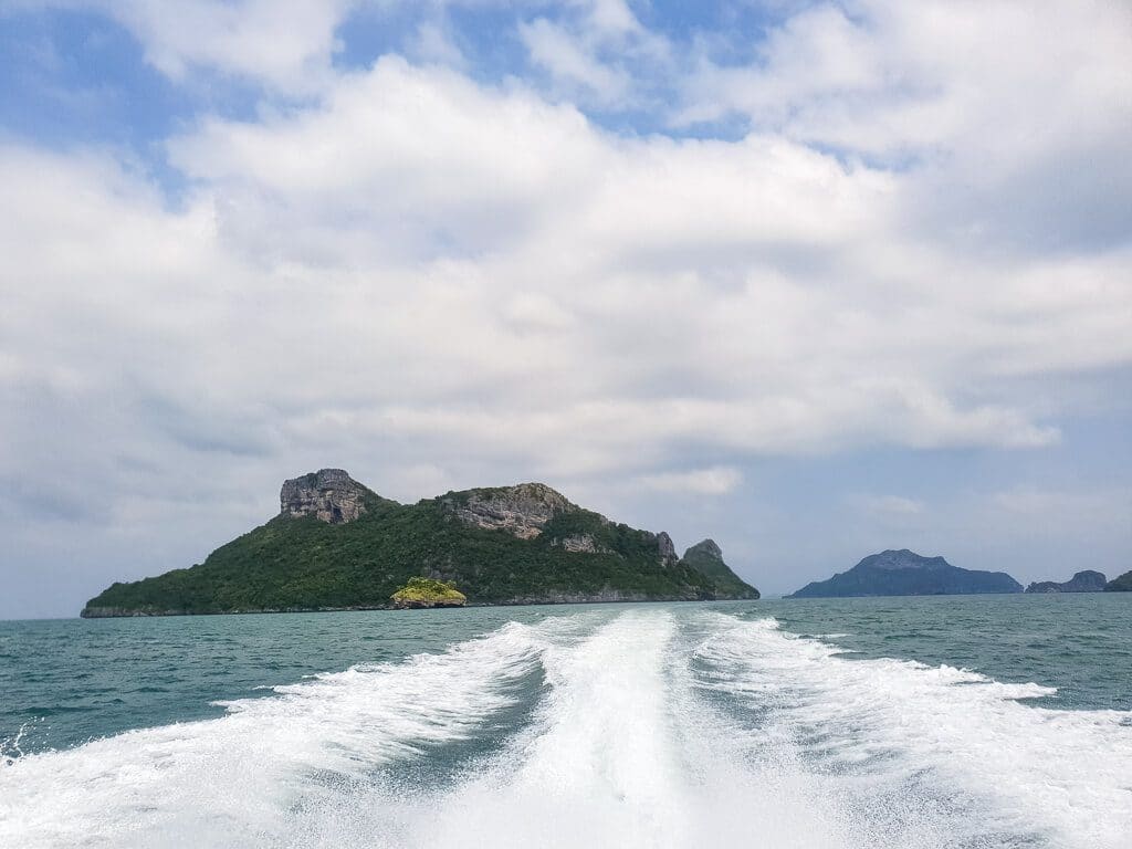 aufgeschäumtes Wasser von einem Boot auf dem Meer - Blick auf eine felsige Insel