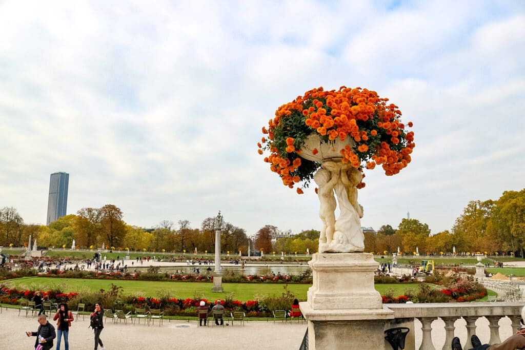 Statue mit bunten Blumen, dahinter eine Gartenanlage