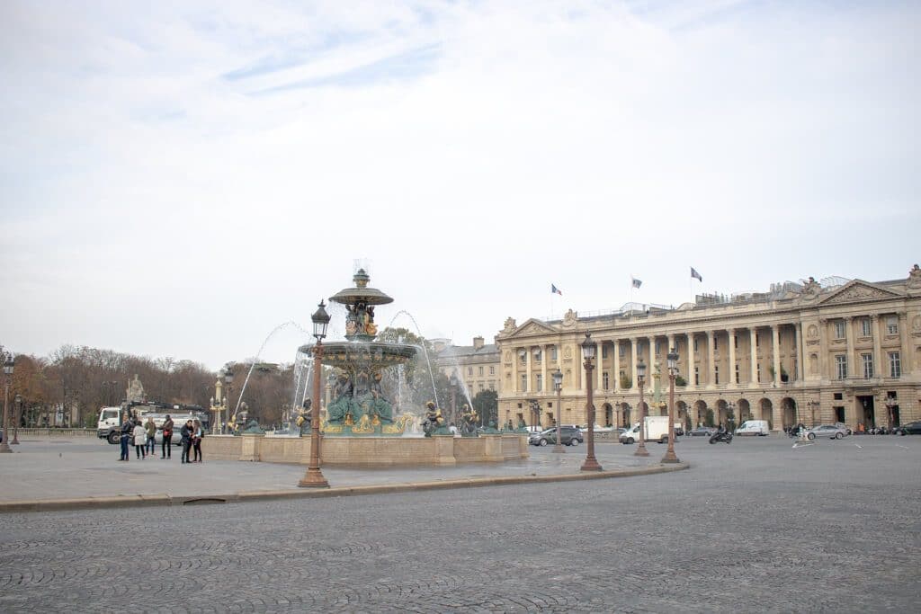 Platz in Paris - mittig ein Brunnen, rechts ein Gebäude mit Säulen