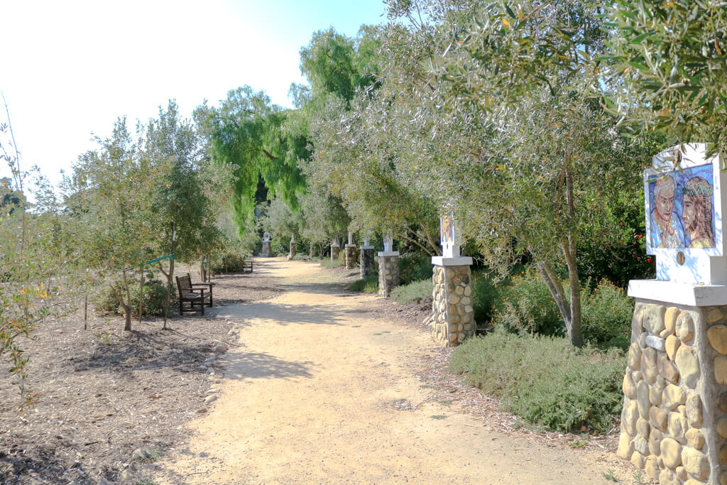 Weg durch einen Olivenhain - rechts stehen mehrere Stationen des Kreuzweg