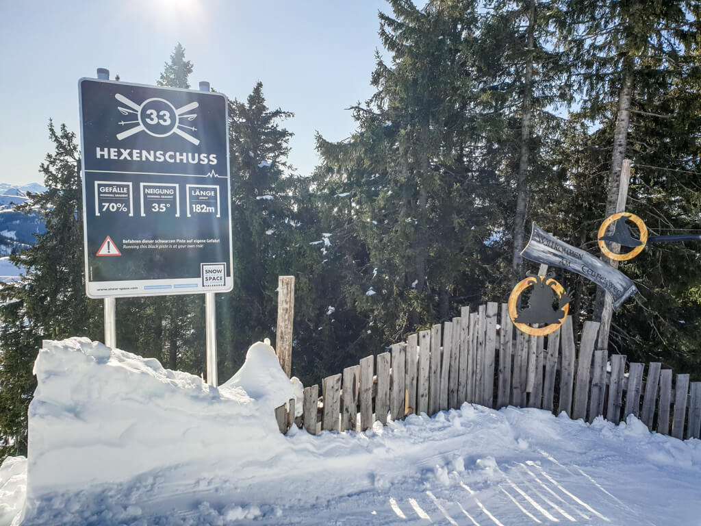 Schild "Hexenschuss" auf einer schneebedeckten Skipiste