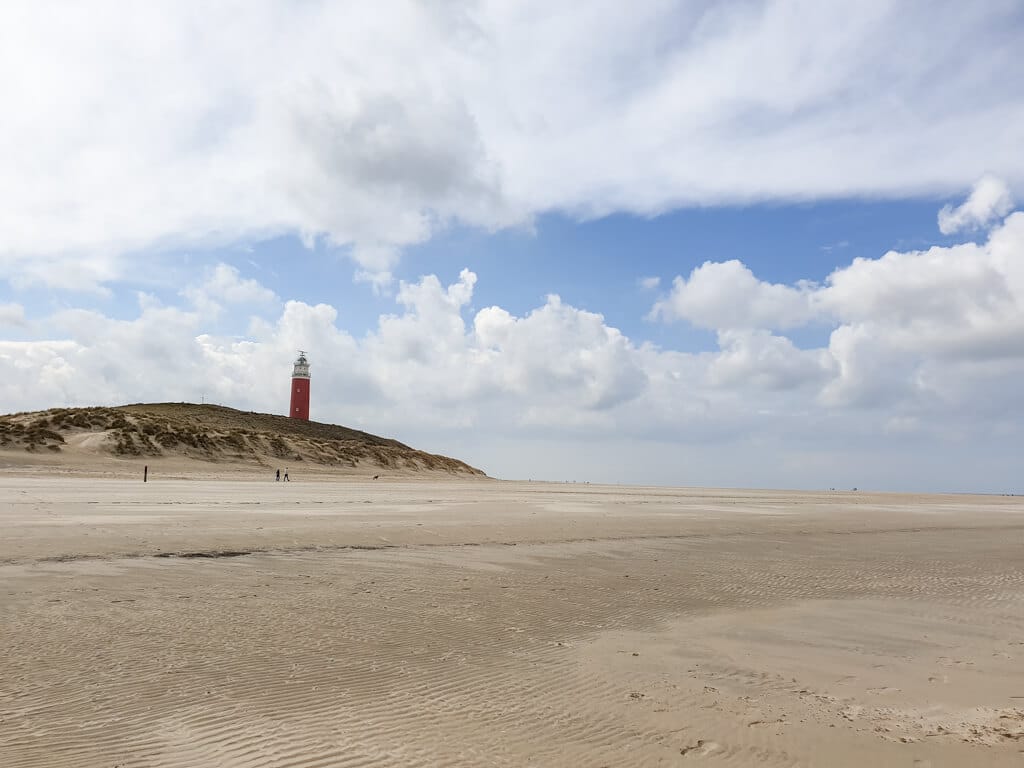 breiter Sandstrand mit Blick auf den Leuchtturm von Texel