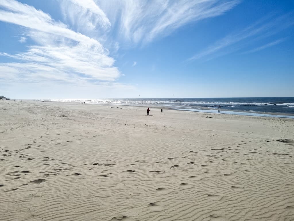 Sandstrand mit einigen Fußabdrücken und dem Meer zur rechten Seite