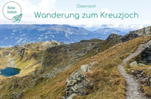 Titelbild "Wanderung zum Kreuzjoch" - Bild zeigt schmalen Wanderweg in den Bergen, links davon ein blauer Bergsee
