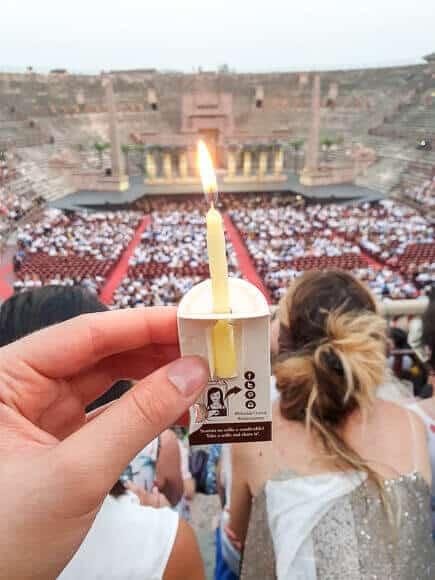 Hand mit Kerze im Vordergrund - dahinter die Arena di Verona
