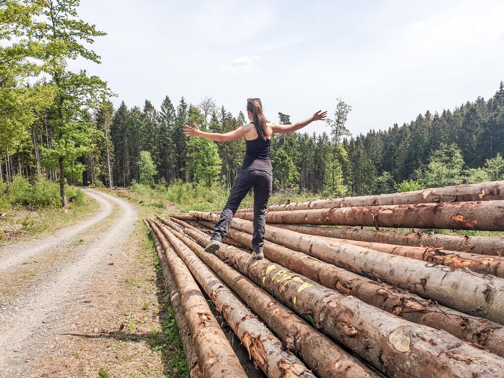 Frau balanciert auf einem Holzstapel im Wald