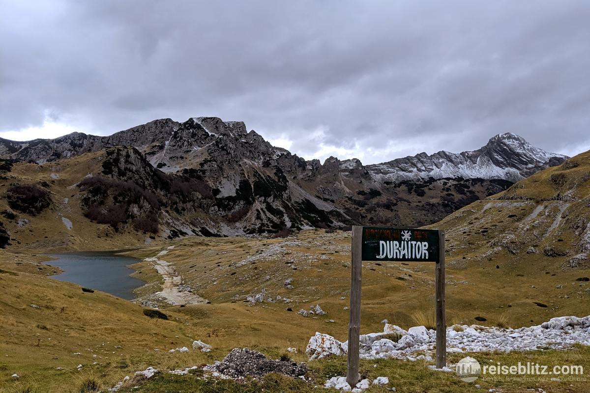Ausblick über Berge und einen See - im Vordergrund ein Schild "Durmitor"